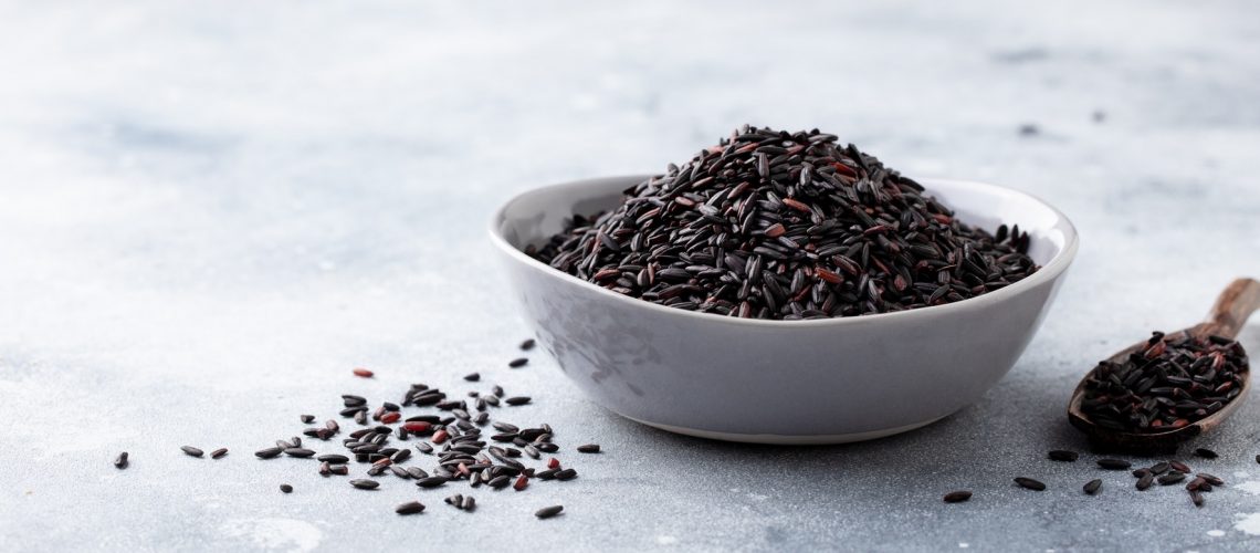 Black wild rice in a bowl. Grey stone background.